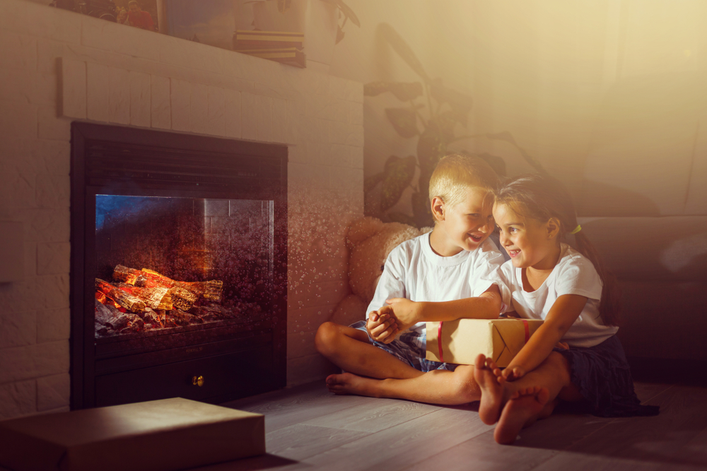 Two children sitting comfortably beside a gas log fireplace in Canberra
