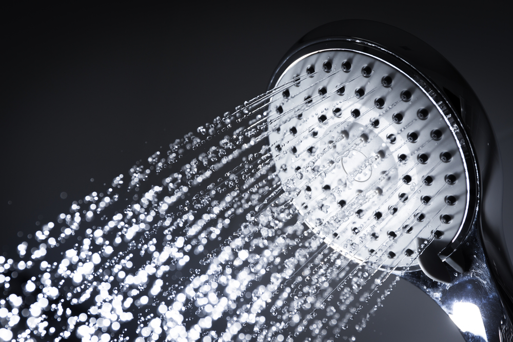 Modern showerhead with water running, showcasing plumbing services in Canberra
